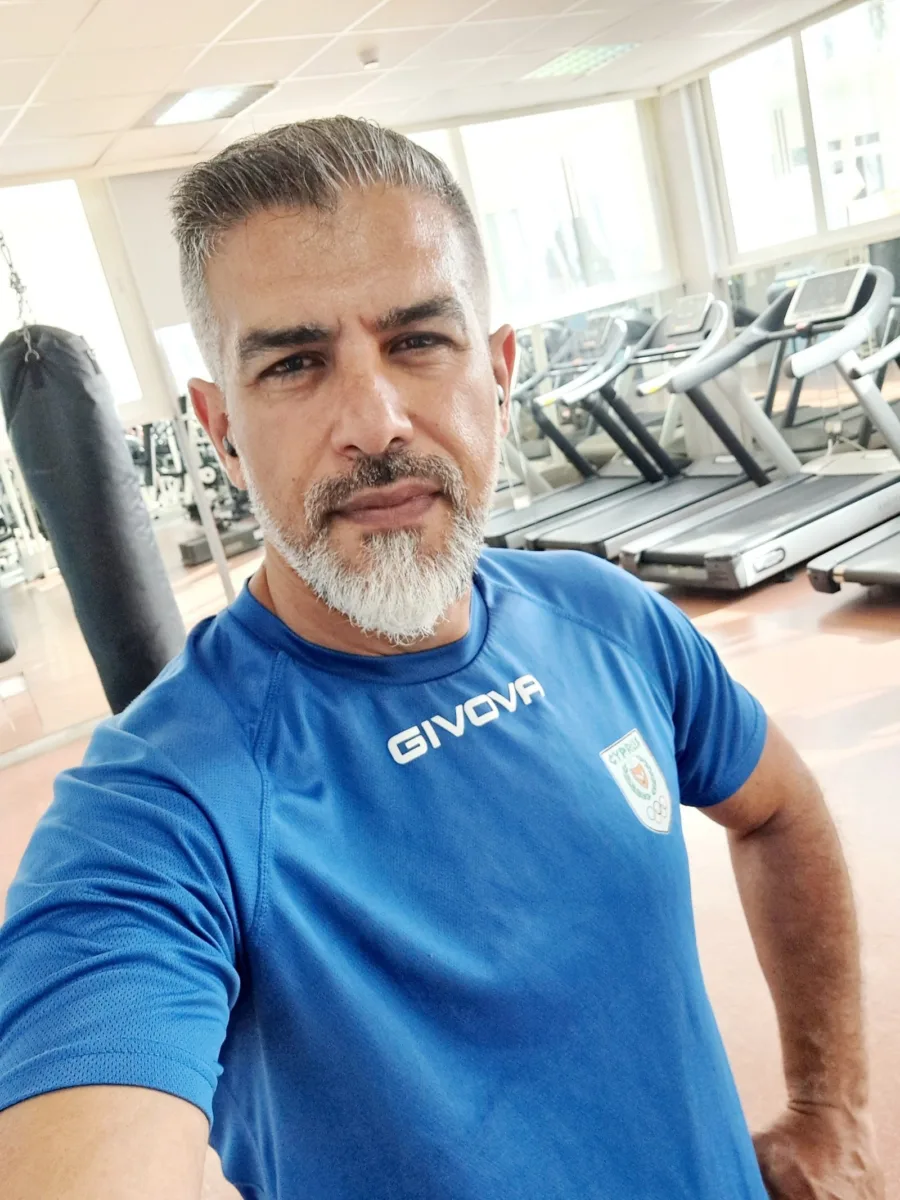 Ramo in a blue training shirt in the gym, treadmills and weight machines behind him