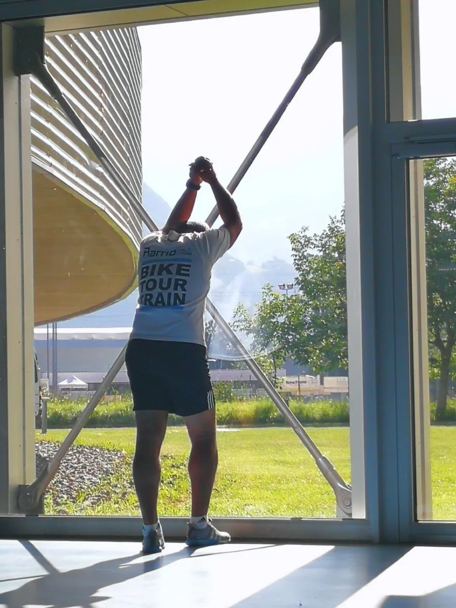 A rider stretching against a tall window frame after a session