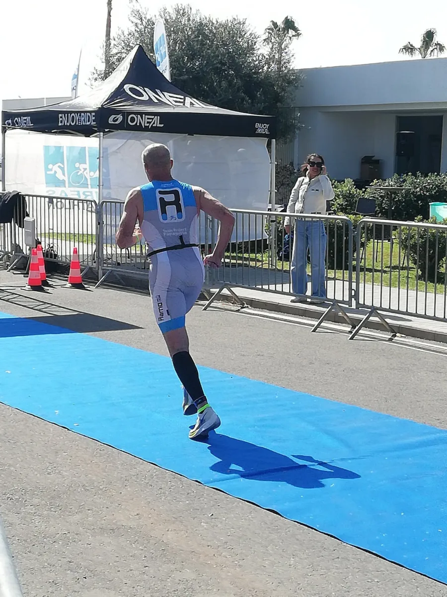 Ramo running down the blue finish chute of a triathlon