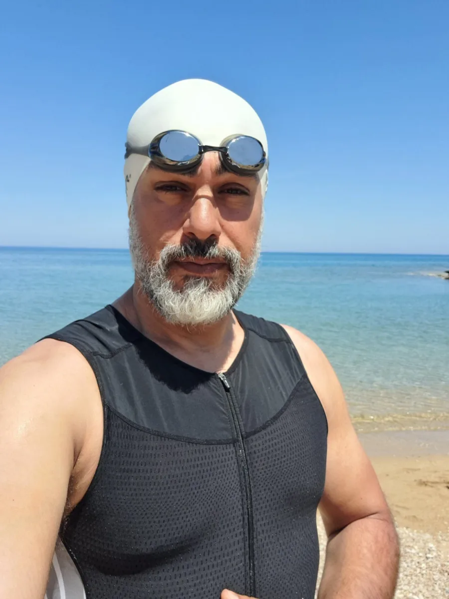 Ramo in a swim top, cap and goggles at the water's edge