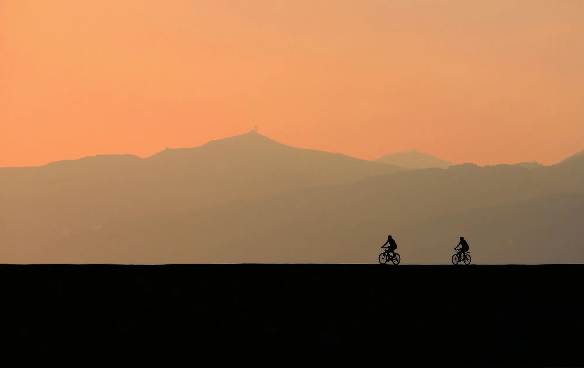 Riders silhouetted on a ridge at sunset