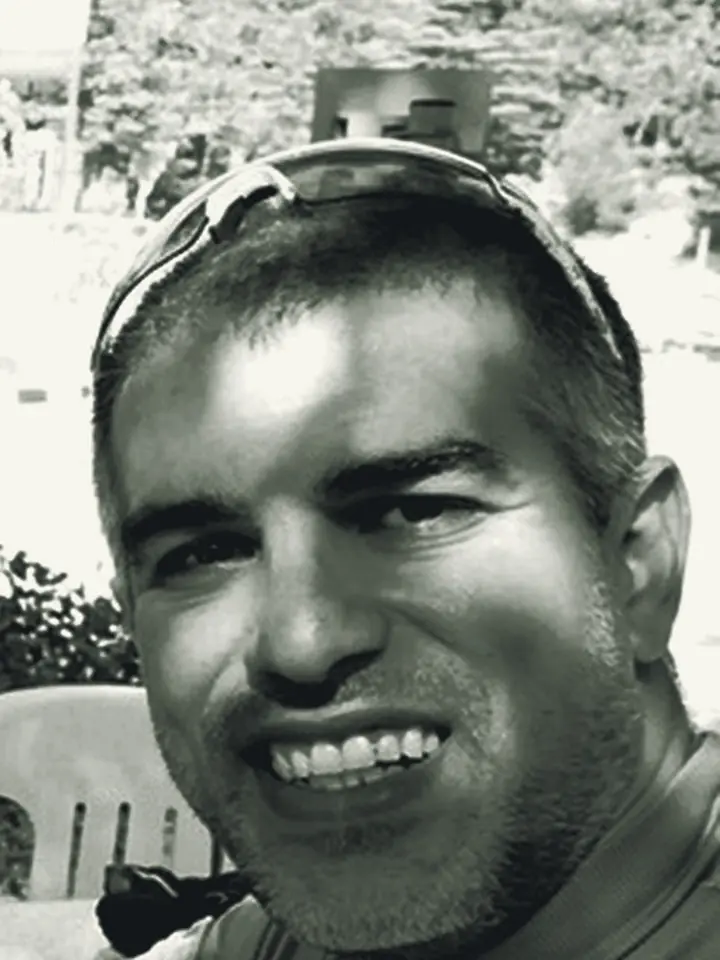 Ramo smiling, sunglasses pushed up on his head, in black and white