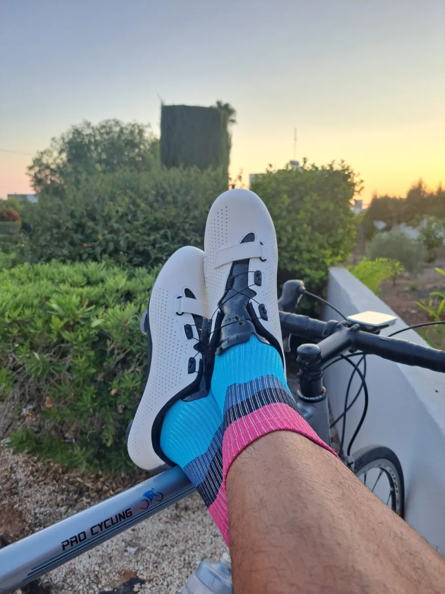 A rider's legs resting on the handlebars of a road bike at sunrise