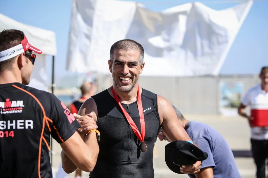 Ramo shaking hands at the finish of a triathlon with a medal round his neck