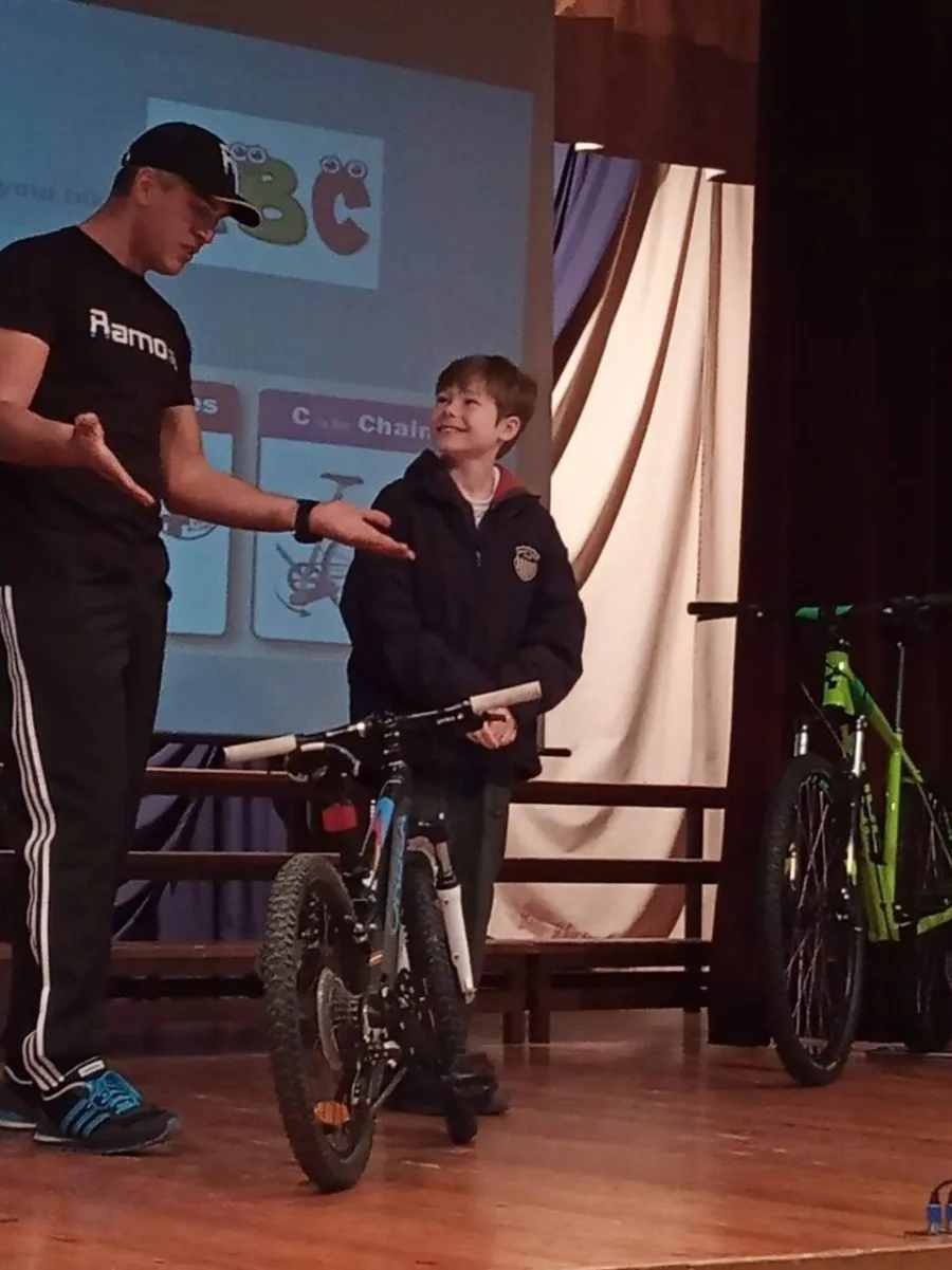 Ramo showing a school pupil how to stand over a mountain bike on stage