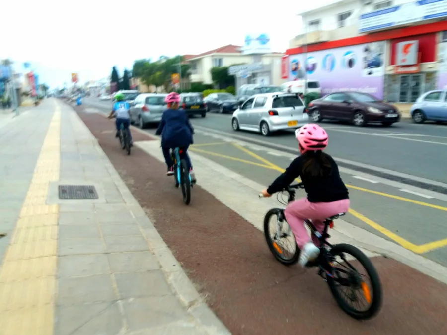 Children riding in a marked cycle lane beside traffic on a main road