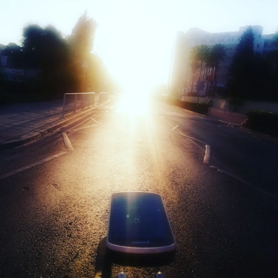 The view over a bar-mounted computer straight into a low sun on an empty road