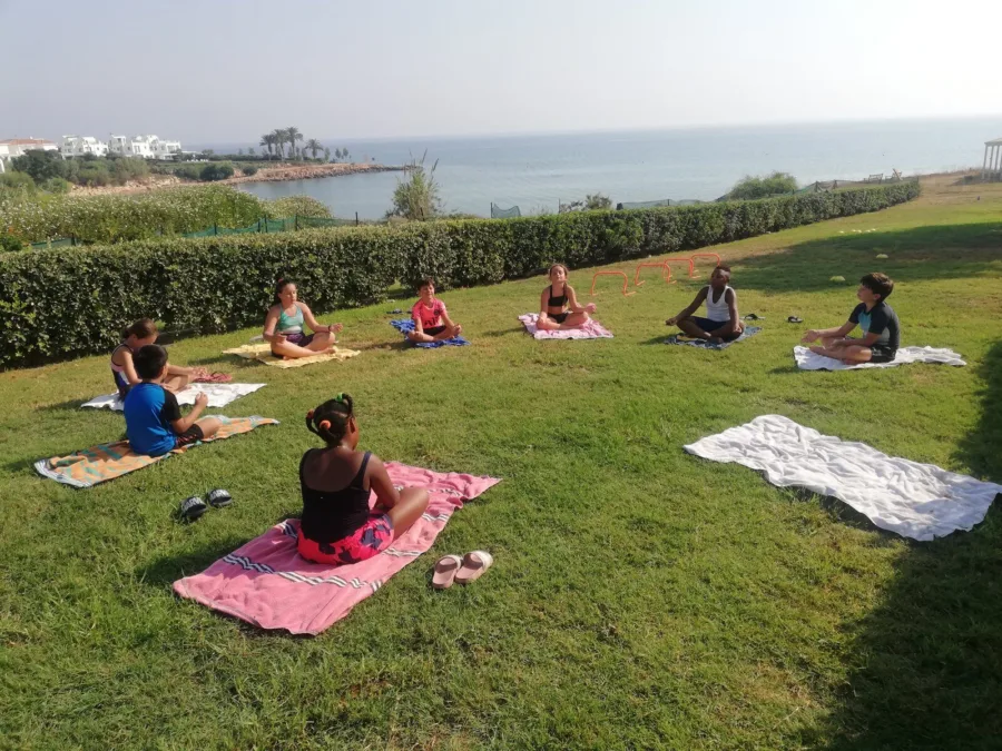 Adults and children spread across a clifftop lawn during a morning session