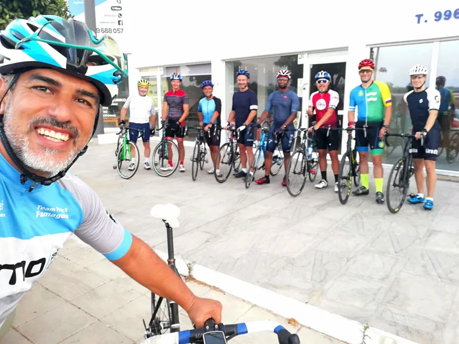 A guide takes a selfie in front of eight riders lined up with their bikes outside a shop, ready to set off