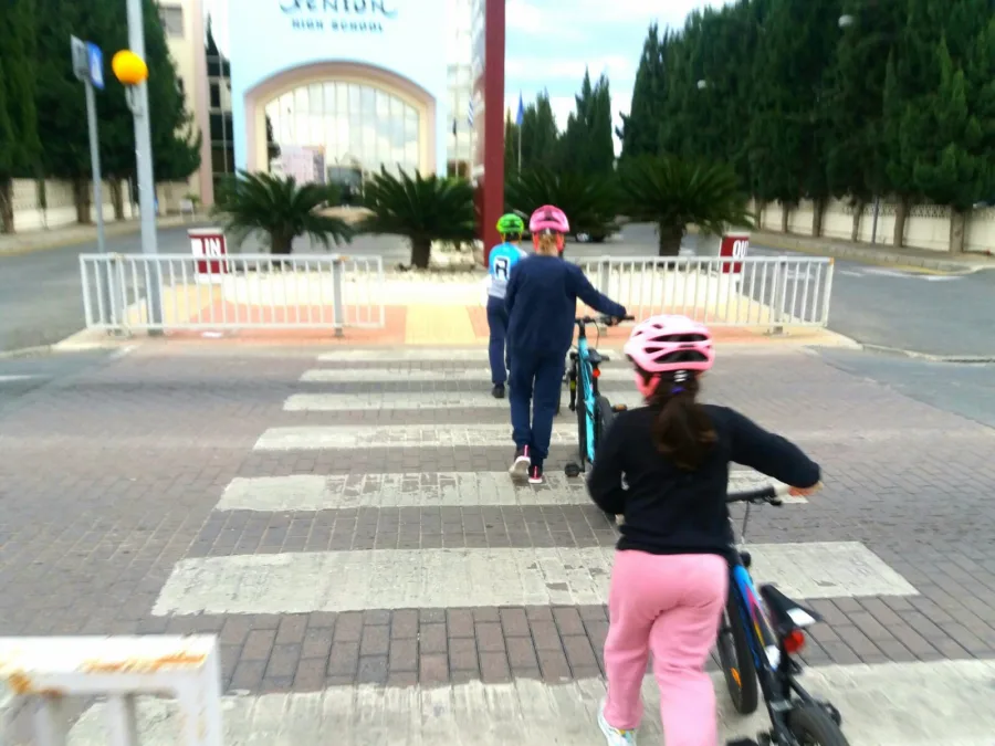 Two children walking their bikes across a marked crossing outside a school