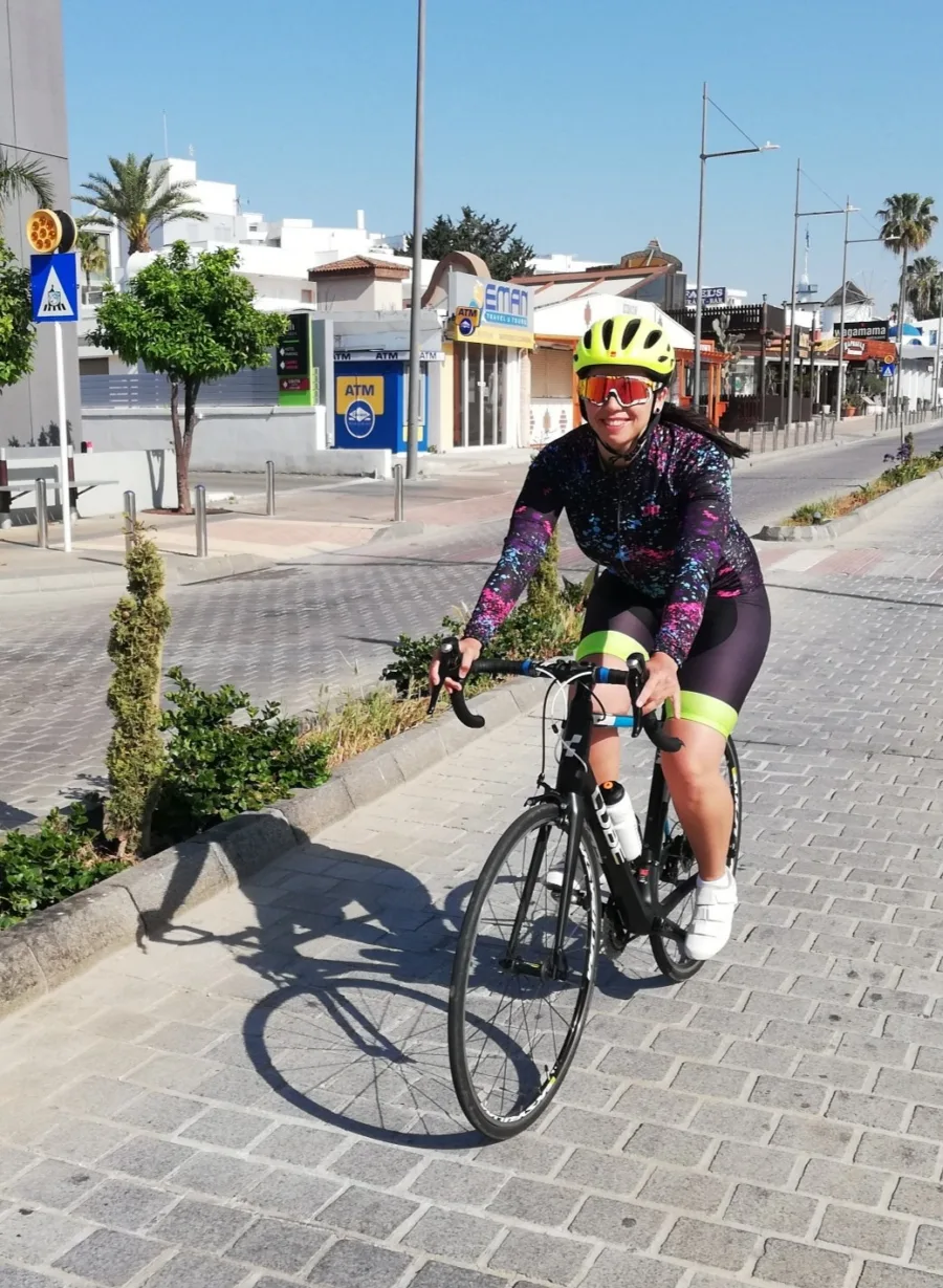 A rider on a road bike smiling on a paved town street early in the morning