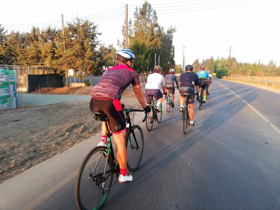 A group of six riding away down a road in low evening light