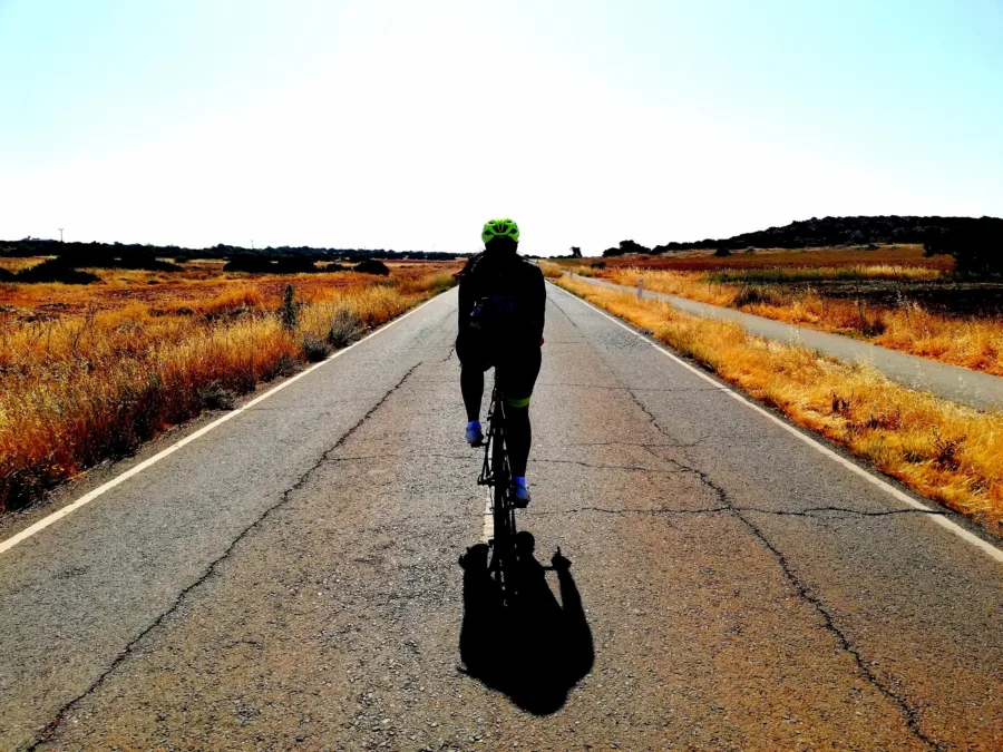 A lone rider on a dead straight road through burnt gold summer fields
