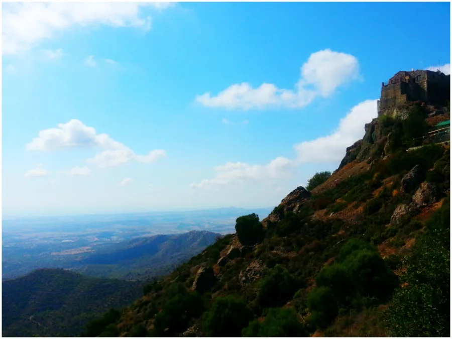A stone monastery on the summit of a steep hill, the plain far below under a big sky