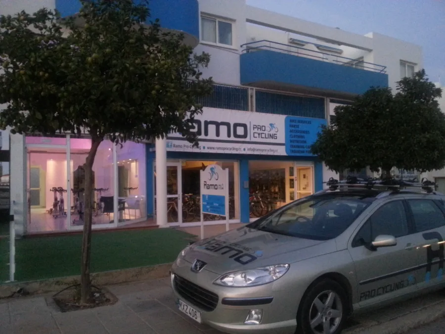 The shop front in the evening with the branded estate car parked outside, bike rack on the roof