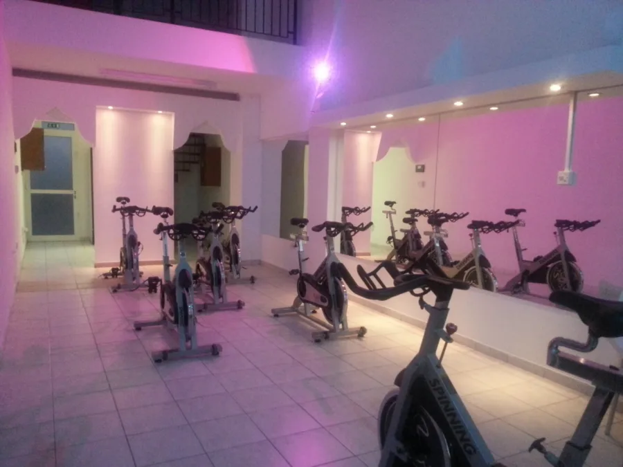 The same spin studio lit pink and violet in the evening, bikes facing the mirrored wall