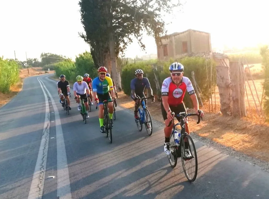 Six riders coming towards the camera on a country road at sunrise, an old stone house behind