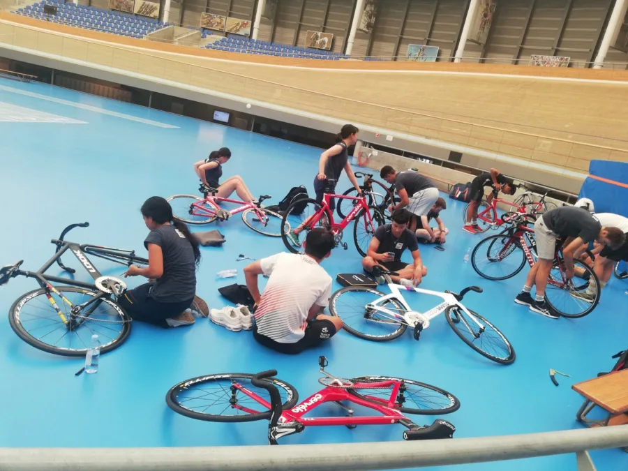 Riders and bikes on the blue infield of an indoor velodrome