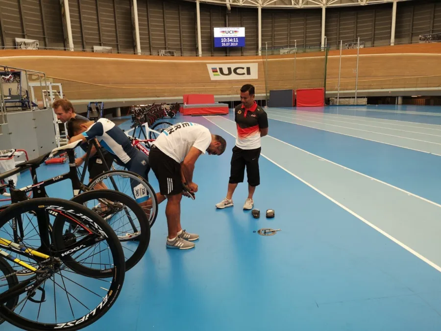Track bikes and riders on the infield of a velodrome under UCI signage