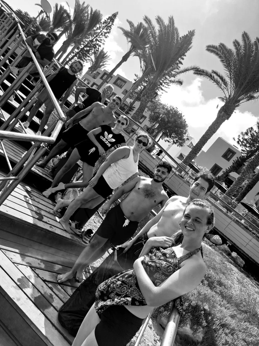 A group training under a shade sail on the boardwalk, in black and white