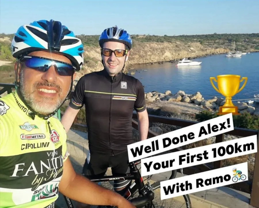 A shared story: a coach and a rider above a small harbour, captioned Well Done Alex! Your First 100km With Ramo