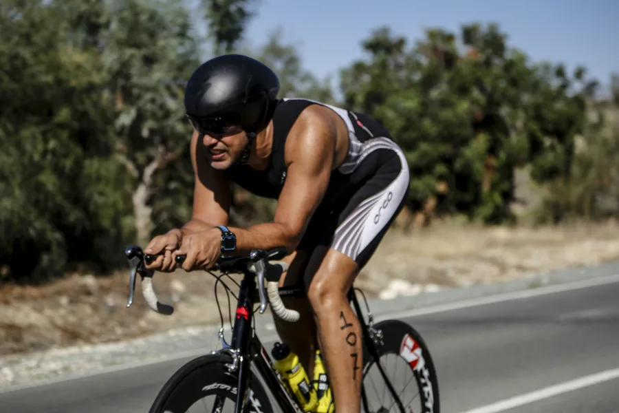 A rider in a black skinsuit and aero helmet down on the time-trial bars on an open road