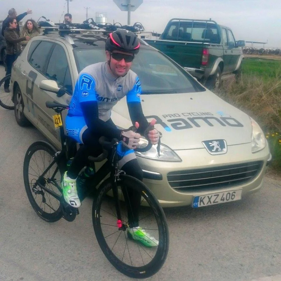 A rider in Ramo kit leaning on the bonnet of the team car