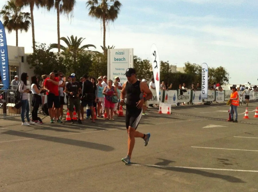 A triathlete running towards the finish past spectators and cones