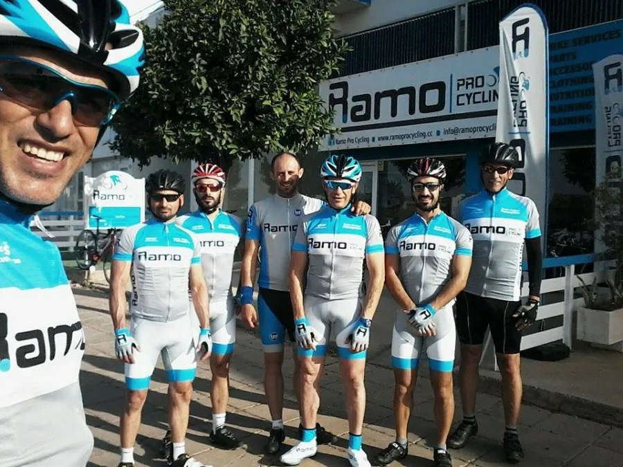 A group of riders in Ramo kit standing with their bikes in front of the shop