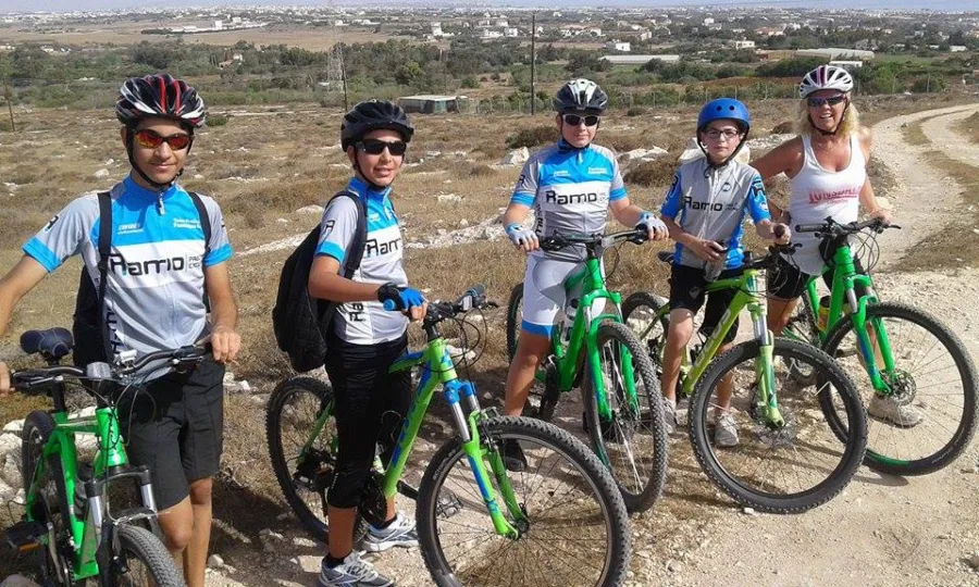 Riders standing with mountain bikes on a hill above a town