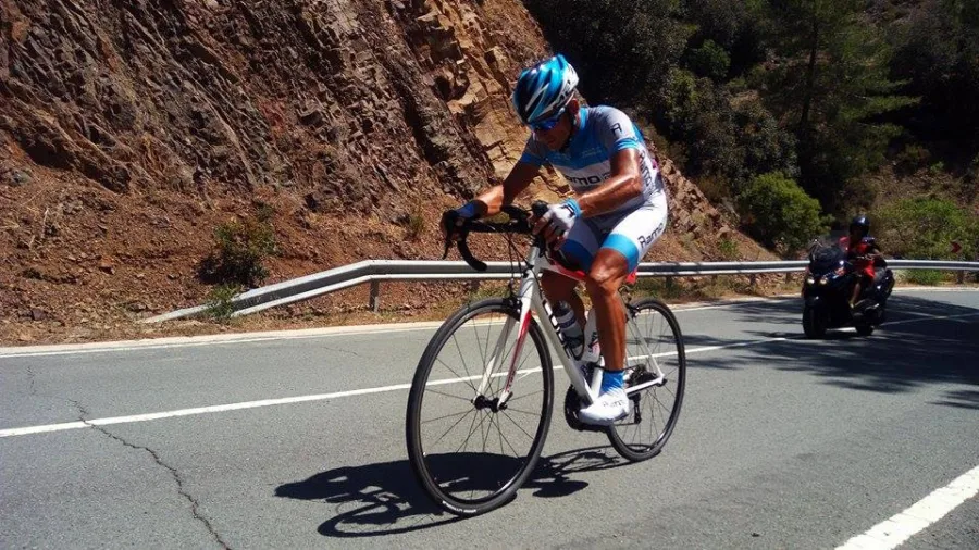A rider climbing past a red rock cutting on a mountain road