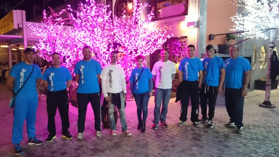 A group in Ramo shirts standing at night in a square under a lit pink blossom tree