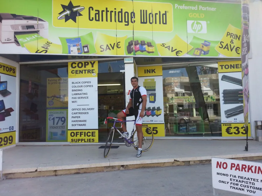A rider standing over a road bike outside a shop front
