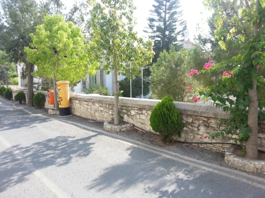 A quiet village street with stone walls, flowers and a yellow postbox