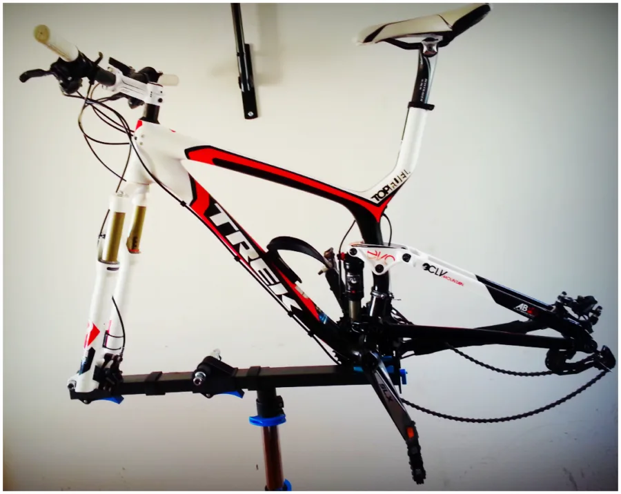 A white and red Trek mountain bike frame held in a workshop stand