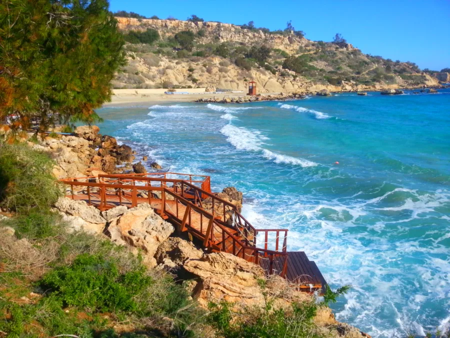 A rocky bay with surf breaking below a wooden boardwalk