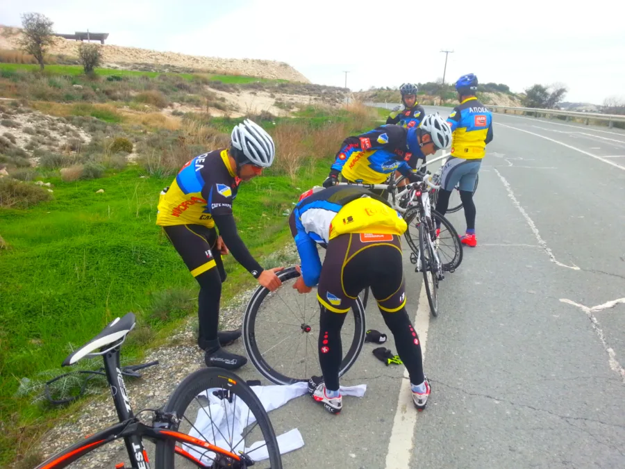 Riders in blue and yellow kit crouched over an upturned bike at the roadside