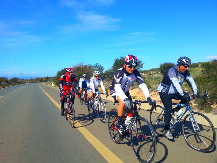 A group of riders spread across a wide road under a blue sky