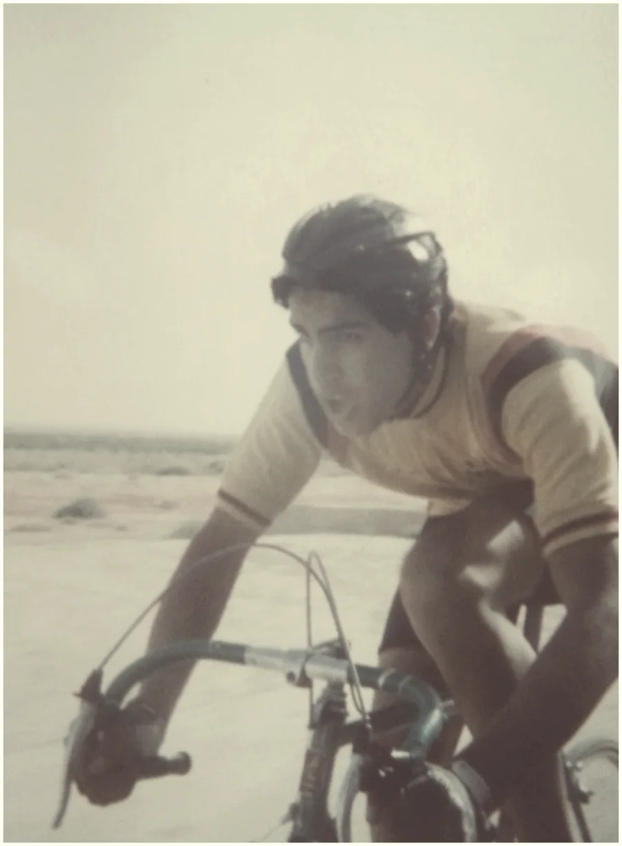 A sepia photograph of a rider in old-style kit on the drops of a steel bike
