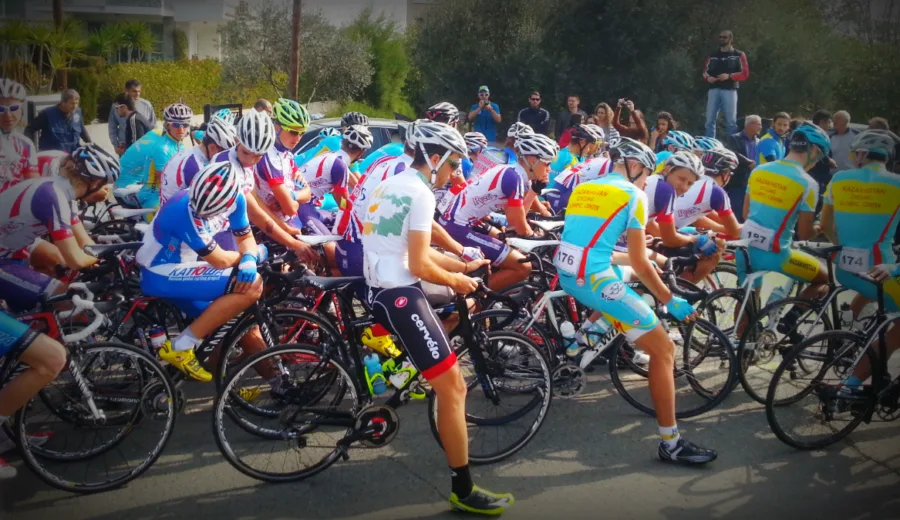 A dense bunch of riders in team kit packed together at a race start