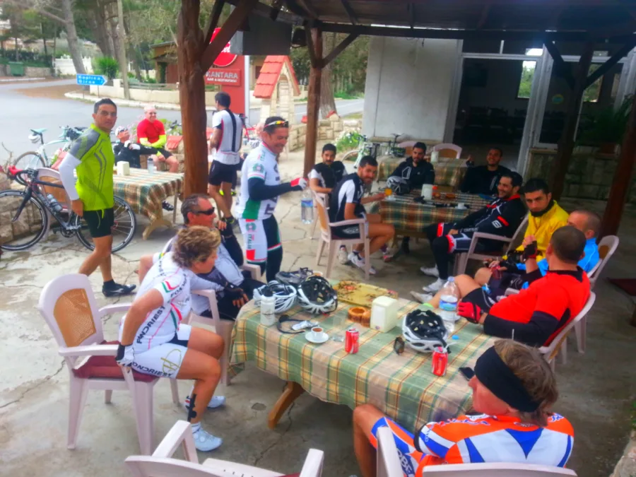 Riders sitting at tables under a wooden shelter with their bikes leaning nearby