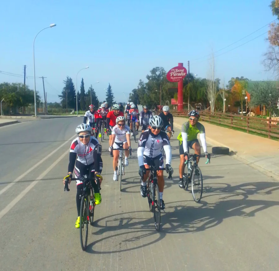 A group of riders coming down a road towards the camera past red flags