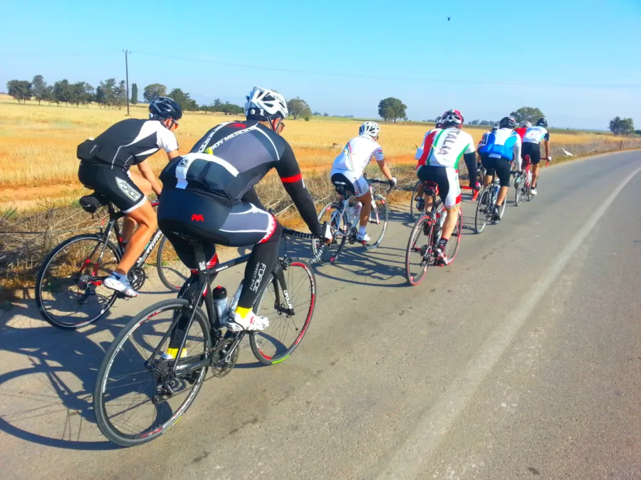 A group of riders on a road running through dry open farmland
