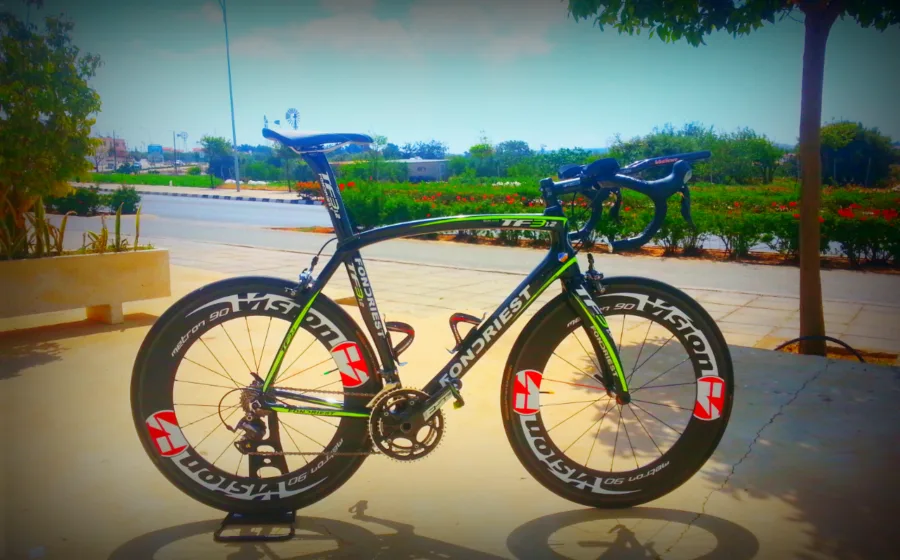 A time-trial bike with deep-section wheels on a paved terrace by the sea