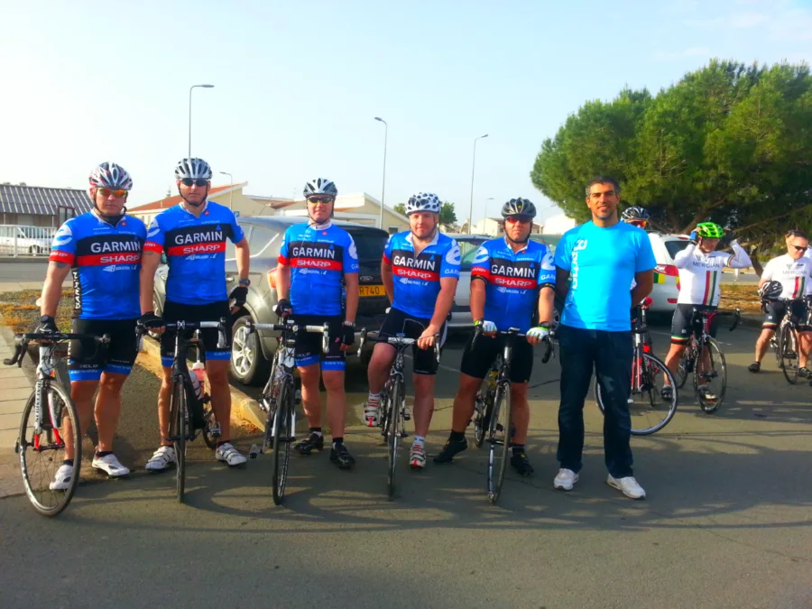 A group of riders in matching kit standing with their bikes on a road