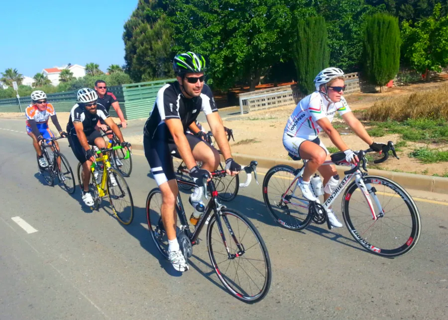 Riders racing in a line on a road shaded by trees