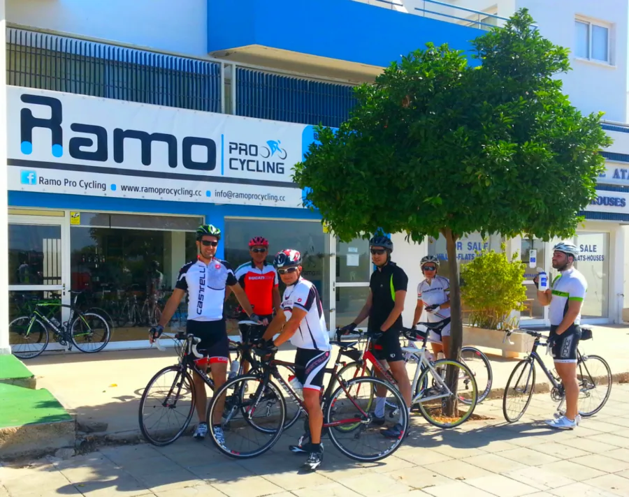 Riders standing with their bikes on the pavement outside the Ramo shop
