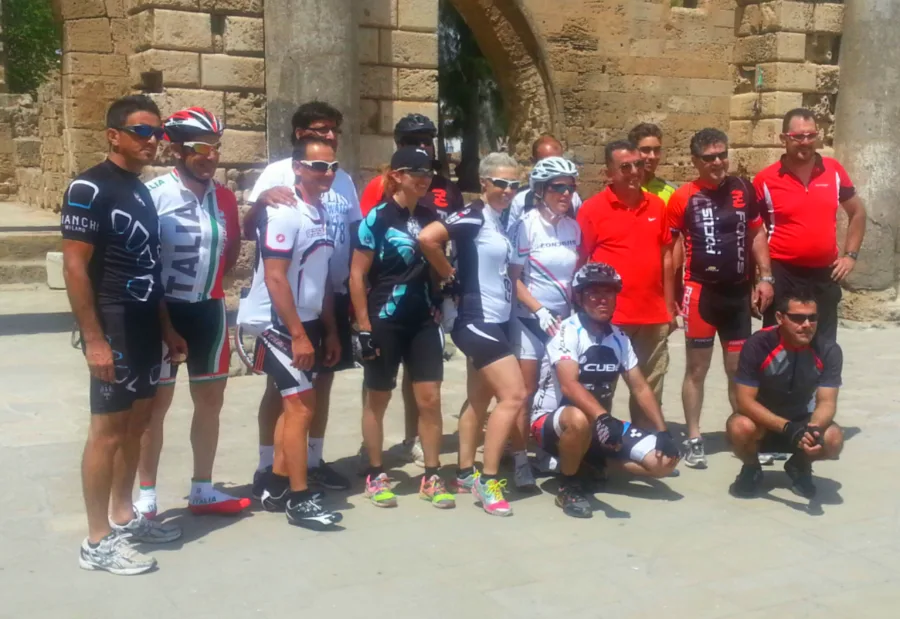 A large group of riders posed under a stone arch