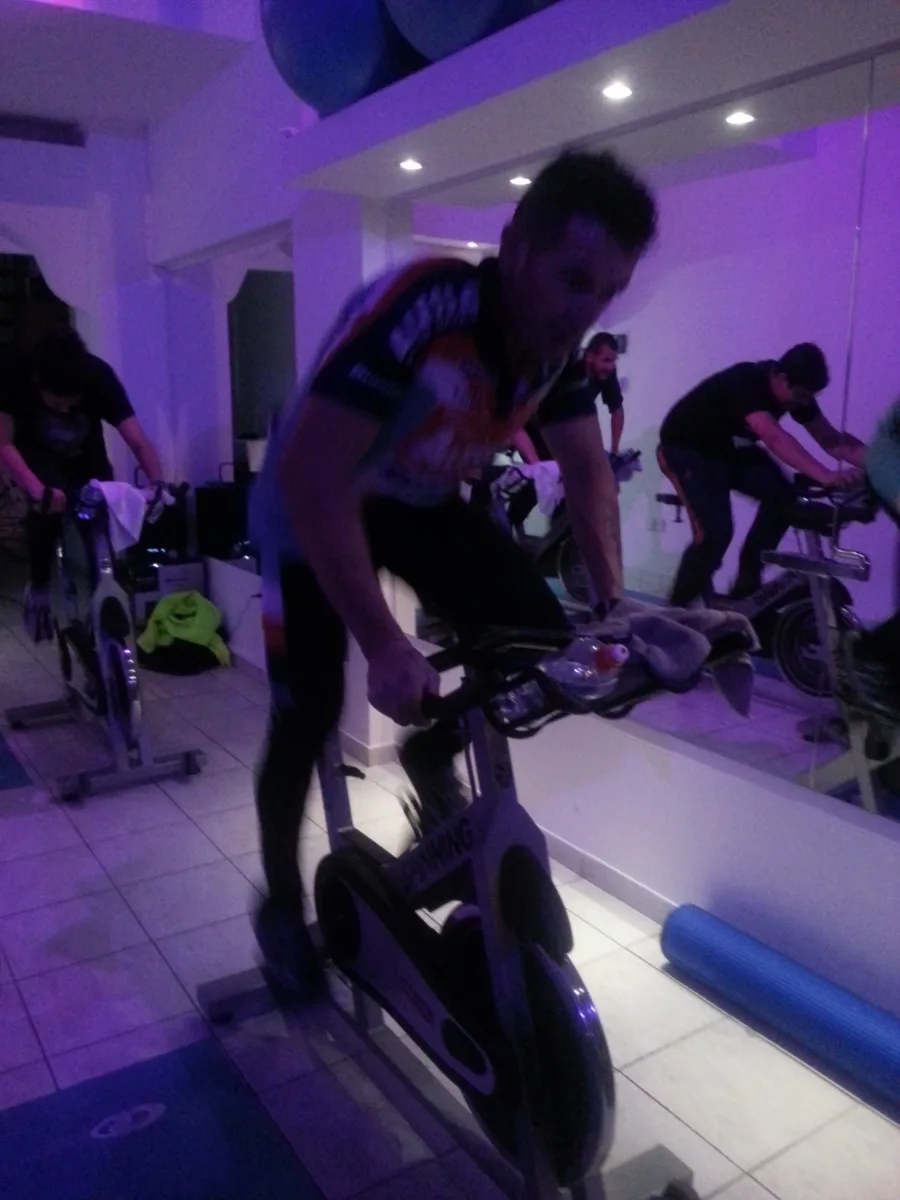 Riders working hard on stationary bikes in a studio under purple light
