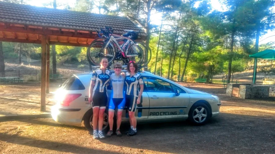 Four riders standing with the support car under a wooden shelter
